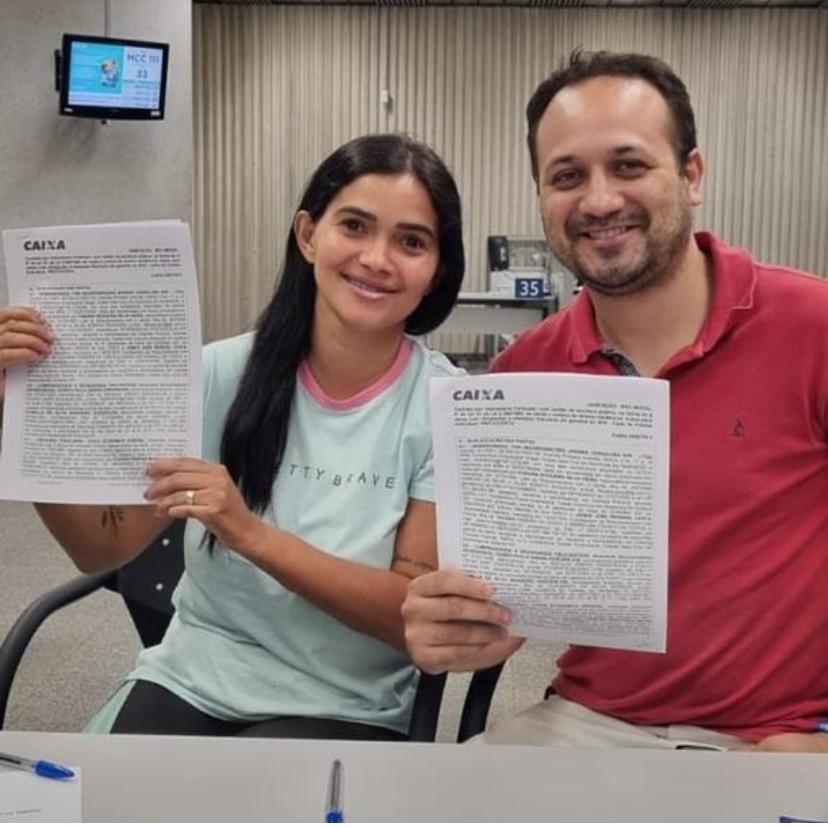 Casal de clientes assinando o contrato de financiamento da Caixa
